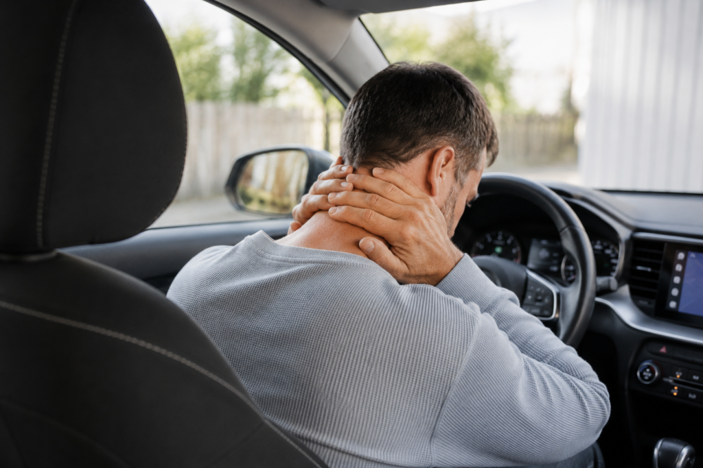 Recovering from whiplash after a car accident as a driver holds his painful neck.