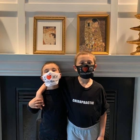 Two young children wearing "I love my chiropractor" masks and shirts, supporting pediatric chiropractic care at Cucci Chiropractic in New York, NY